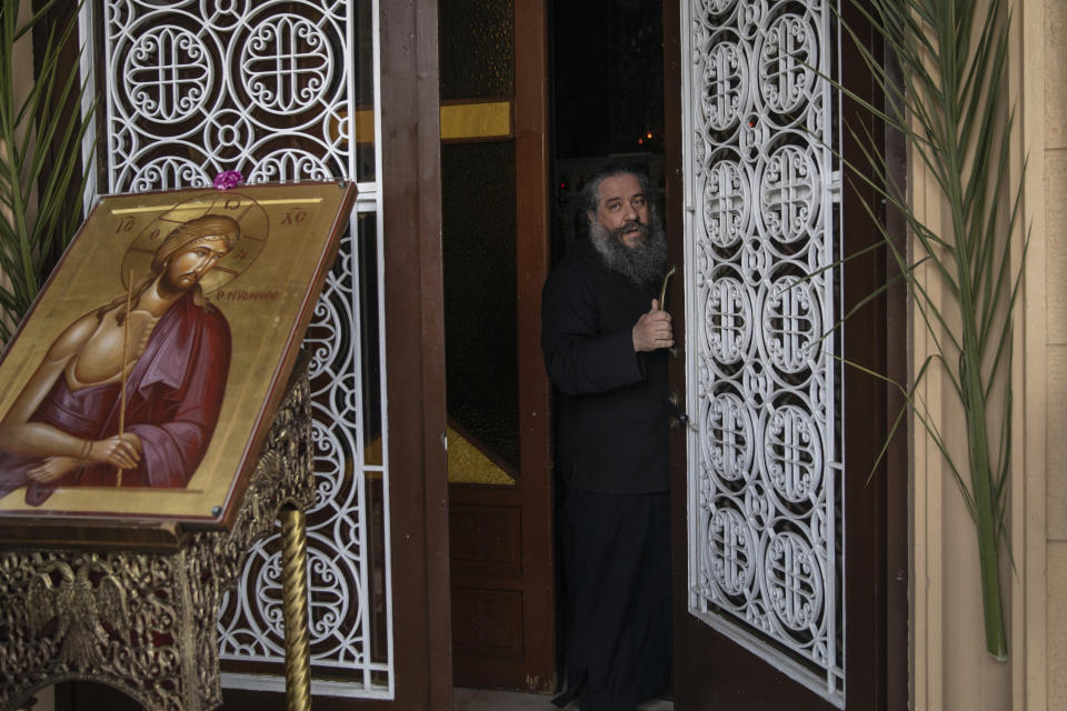 In this Tuesday, April 14, 2020 photo a Greek Orthodox priest closes the entrance of a church in the start of the Holy Tuesday ceremony held without worshippers in Athens, Greece, during a lockdown order by the government to prevent the spread of the coronavirus. For Orthodox Christians, this is normally a time of reflection, communal mourning and joyful release, of centuries-old ceremonies steeped in symbolism and tradition. But this year, Easter - by far the most significant religious holiday for the world's roughly 300 million Orthodox - has essentially been cancelled. (AP Photo/Petros Giannakouris)
