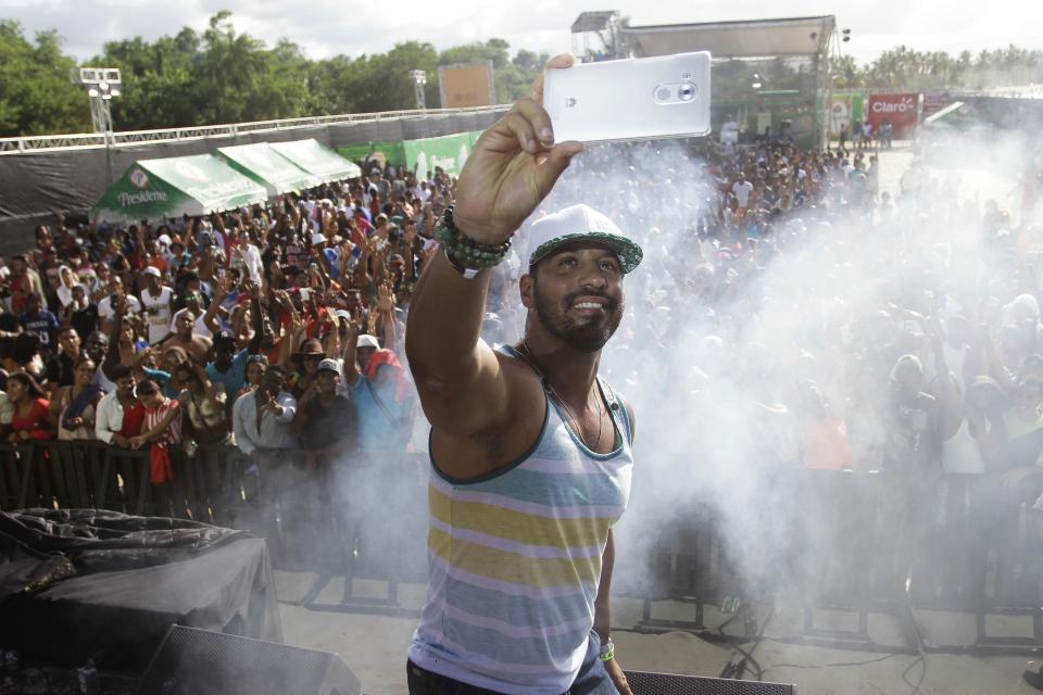 In this Aug. 14, 2016 photo, television presenter Joel Lopez takes a selfie as he works as a presenter during a concert in Santo Domingo, Dominican Republic. Lopez was injured the night of the attack on former Boston Red Sox slugger David Ortiz, who was also injured, on the night of June 9 in Santo Domingo. (AP Photo/Roberto Guzman)