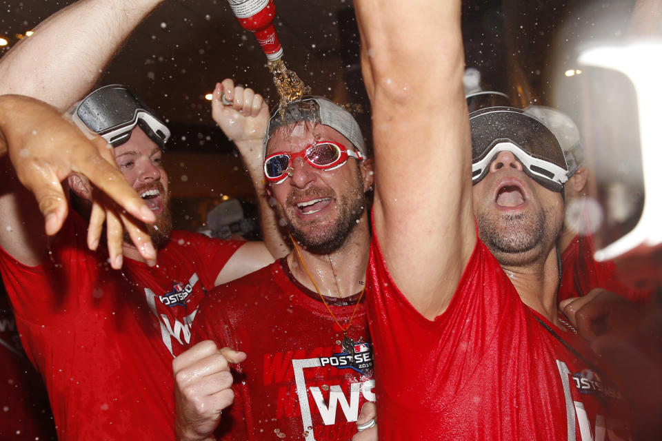 In this photo taken Oct. 1, 2019, Washington Nationals pitcher Max Scherzer, center, celebrates with teammates after winning a National League wild-card baseball game against the Milwaukee Brewers in Washington. All eyes will be on Scherzer at the World Series. And that is fitting in many ways. The Nationals star has an unusual optical condition: one eye blue, one brown. The Houston Astros, however, need only concern themselves about his arm. (AP Photo/Patrick Semansky)