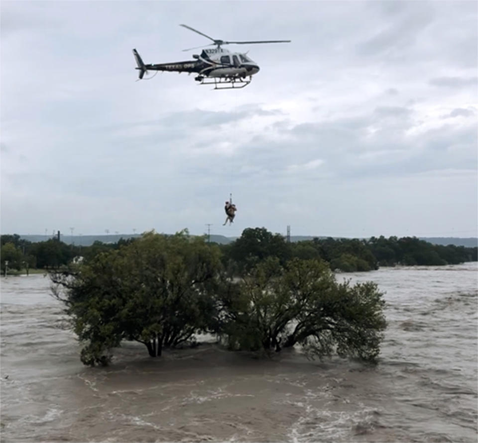 This photo from video provided by the Texas Parks and Wildlife Department shows a helicopter crew from the Texas Department of Public Safety performing a rescue from the South Llano River near Junction, Texas, on Monday, Oct. 8, 2018. Rescue crews in boats and helicopters are searching for several people missing since heavy rain washed away a recreational vehicle park in the small West Texas city. (Texas Parks and Wildlife Department via AP)