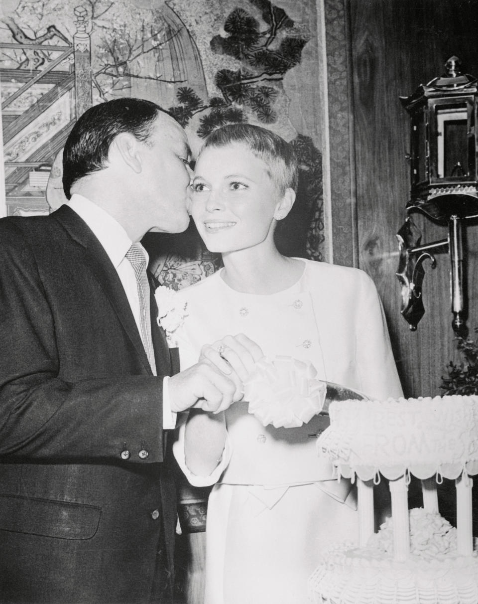 Singer Frank Sinatra in a dark suit, kisses his new bride, formerly Mia Farrow, who has very short hair, after she had cut into their wedding cake after vows were exchanged at the Sands Hotel.