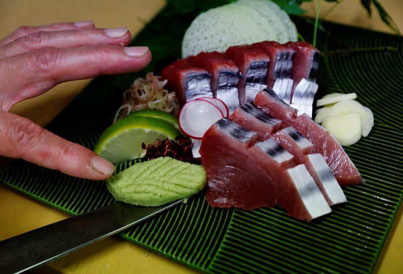 Noriaki Ito,head chef of restaurant Tsukasa, puts wasabi next to sashimi slices of raw katsuo in his kitchen in Kochi