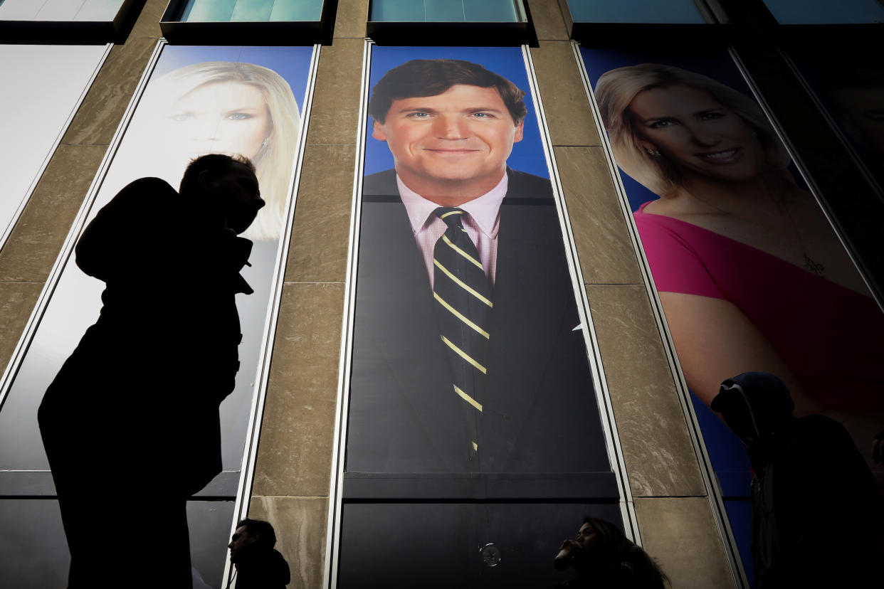 People pass by a promo of Fox News host Tucker Carlson 