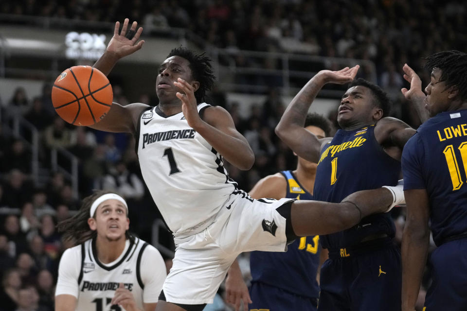 Providence guard Jayden Pierre, front left, and Marquette guard Kam Jones, second from right, vie for a rebound during the first half of an NCAA college basketball game Tuesday, Dec. 19, 2023, in Providence, R.I. (AP Photo/Steven Senne)