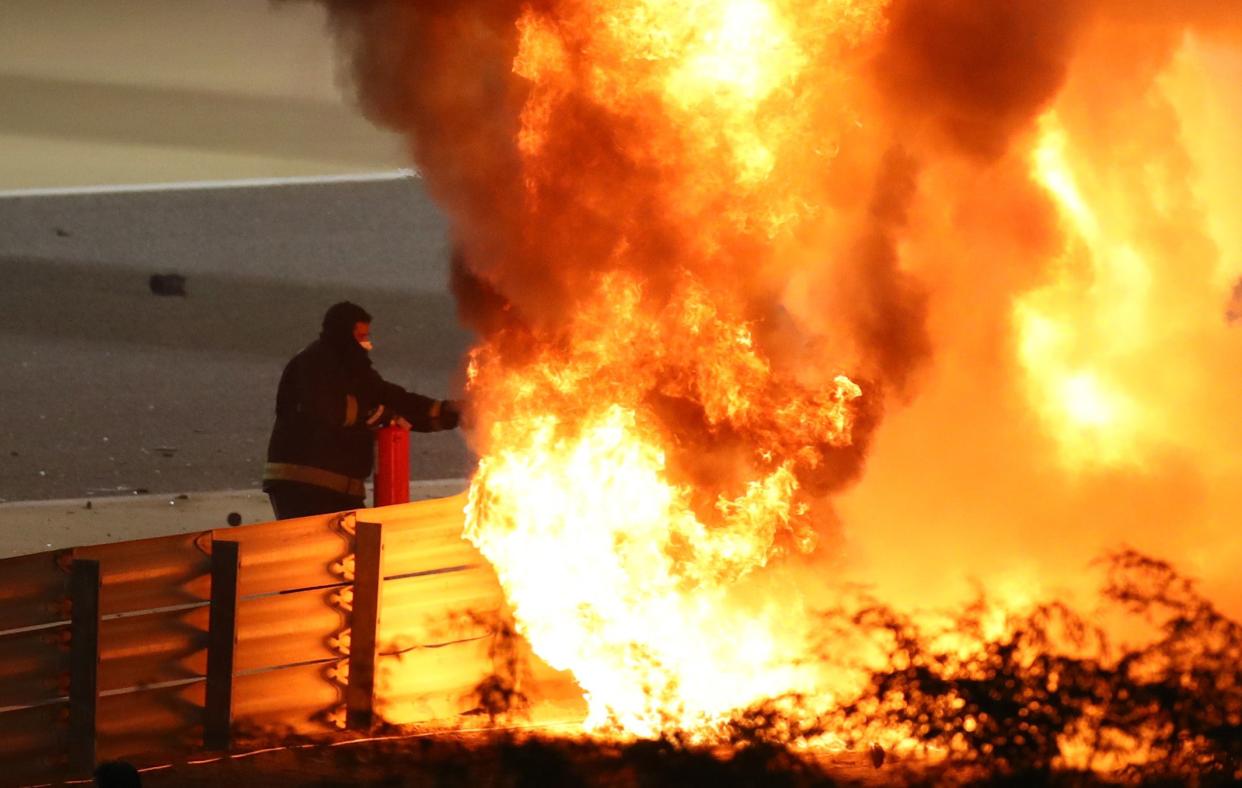 A fire marshal attempts to put out the flames of Romain Grosjean’s Haas after an accident on lap one (Reuters)