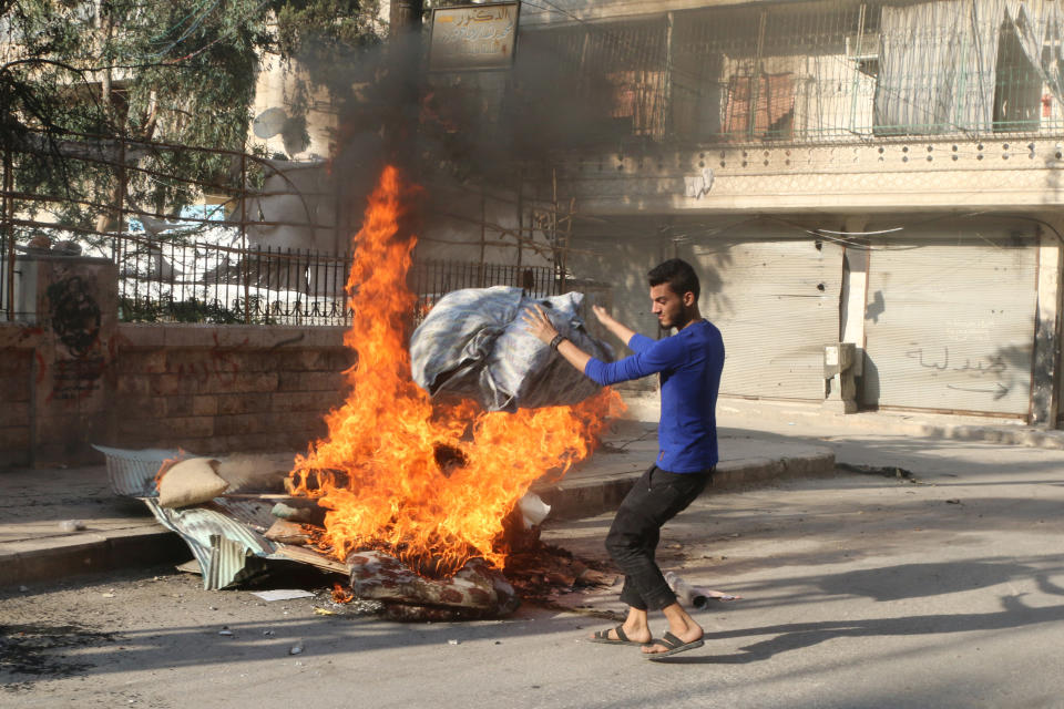 A man burns beddings, which activists said are used to create smoke cover from warplanes, in Aleppo, Syria on Aug. 1, 2016.