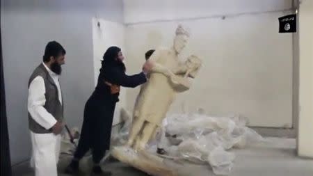 A man topples a statue in a museum at a location said to be Mosul in this still image taken from an undated video. REUTERS/Social media Web site via Reuters TV