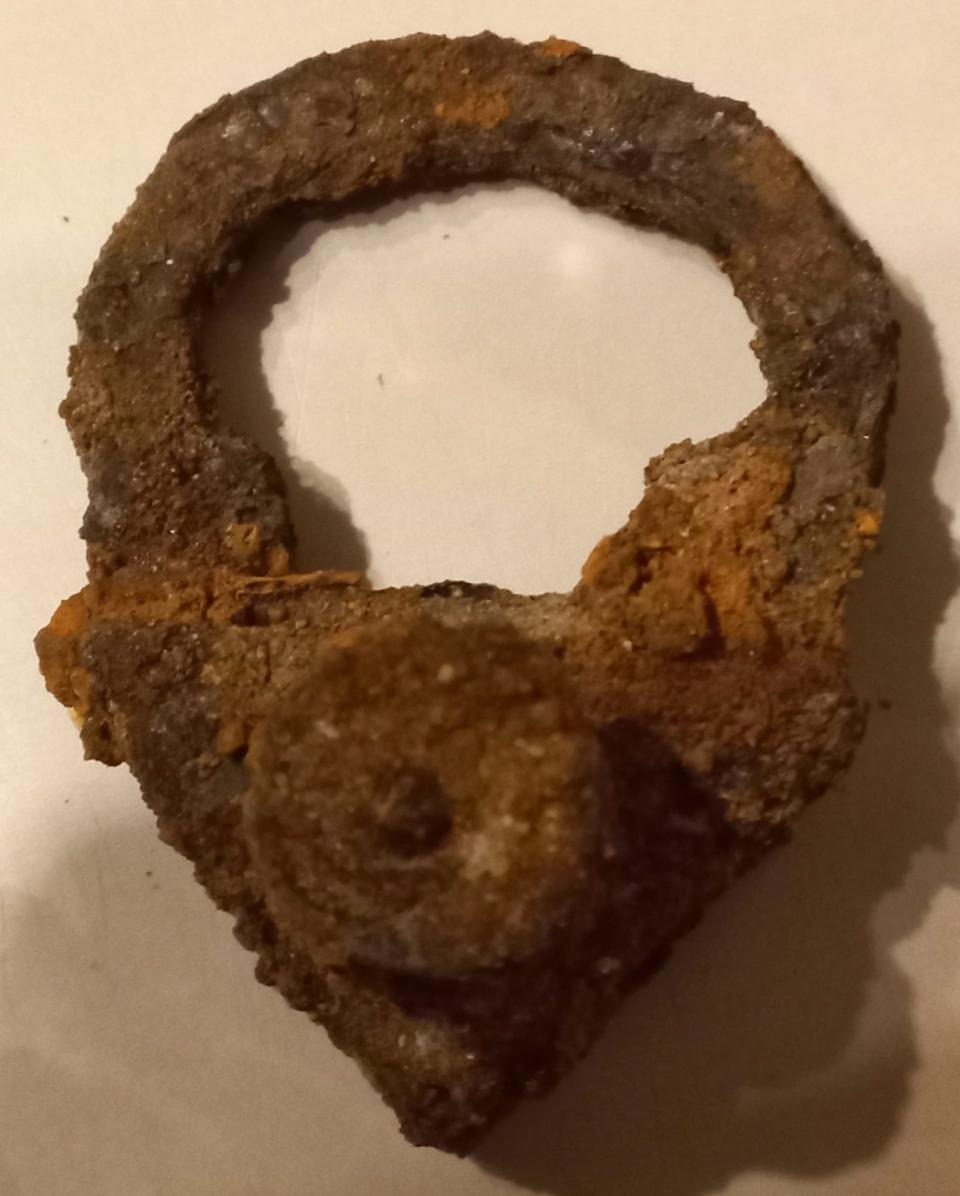 A photo of the triangular padlock found attached to a child's skeletal remains.