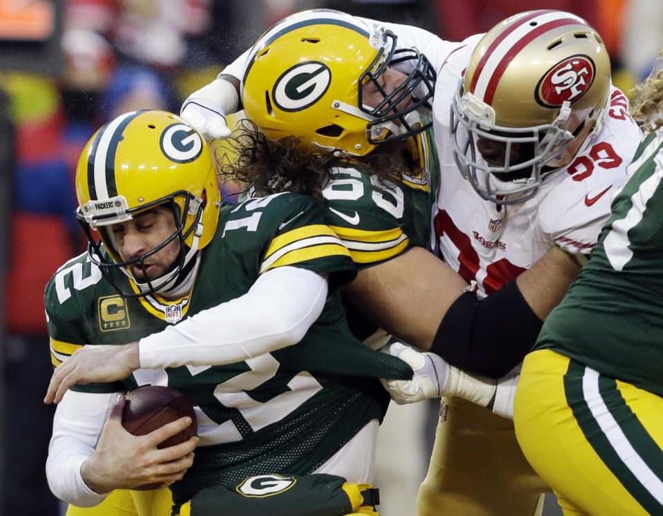 San Francisco 49ers outside linebacker Aldon Smith, right, grabs Green Bay Packers quarterback Aaron Rodgers (12) as Smith fights against the Packers offensive tackle David Bakhtiari (69) during the first half of an NFL wild-card playoff football game, Sunday, Jan. 5, 2014, in Green Bay, Wis. (AP Photo/Mike Roemer)