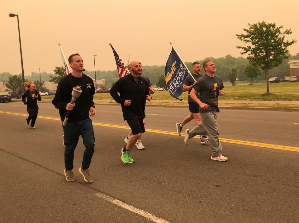 Runners from the Ontario County Sheriff's Office take off from the Lowe's parking lot on their way to Geneva through the orange smoky haze caused by Canadian wildfires as part of the Finger Lakes Law Enforcement Torch Run for Special Olympics.
