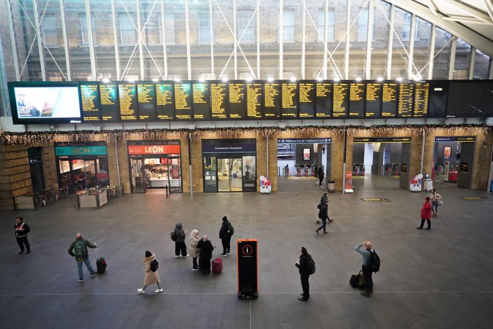 Passengers view departure boards at Kings Cross station in London (PA)