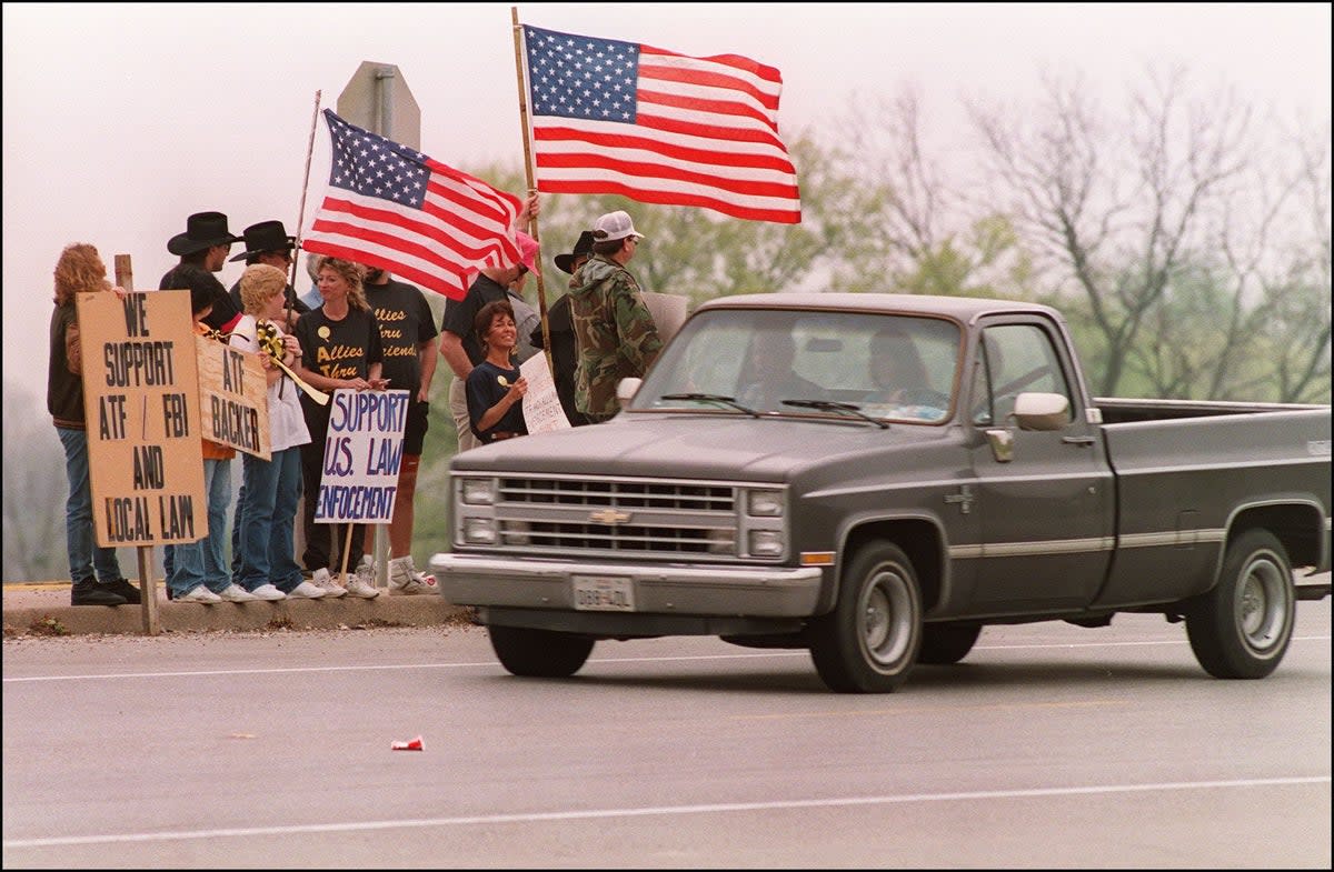 Advocates of the Bureau of Alcohol, Tobacco and Firearms (ATF) shown in a file photo dated 28 March 1993 standing beside the turnoff to the Branch Davidian cult compound, supporting the federal agency involved in the cult shootout (AFP FILES/AFP via Getty Images)