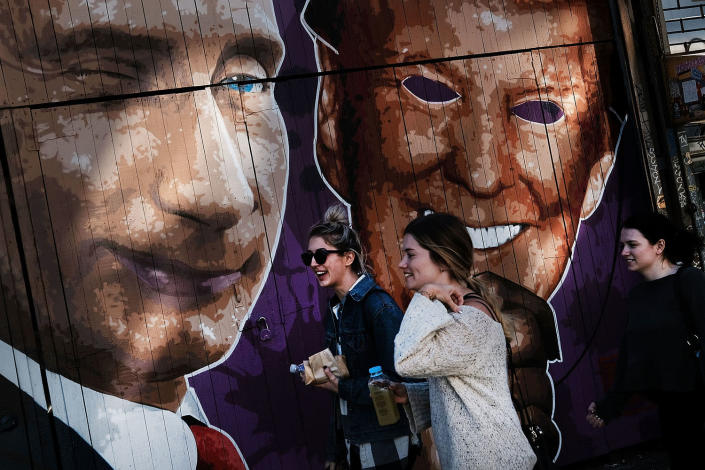 <p>Pedestrians walk past a mural depicting a winking Vladimir Putin taking off his Donald Trump mask, painted on a storefront outside of the Levee bar in Brooklyn,NY, Feb. 25, 2017. The mural, painted by Damien Mitchell, sits in the popular Williamsburg neighborhood and has become a minor attraction with people photographing and taking selfies beside it. (Photo: Spencer Platt/Getty Images) </p>