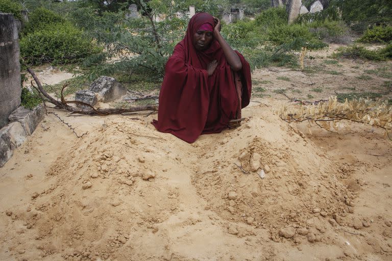 Fatuma Abdi Aliyow se lamenta junto a las tumbas de sus dos hijos muertos por enfermedades relacionadas con la desnutrición, en un campamento para desplazados, el 3 de septiembre de 2022, en las afueras de Mogadiscio, Somalia. (AP Foto/Farah Abdi Warsameh)