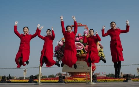 Hostesses jump in the air on Tiananmen square during the closing session of the 19th Communist Party Congress in Beijing - Credit: NICOLAS ASFOURI/AFP/Getty Images