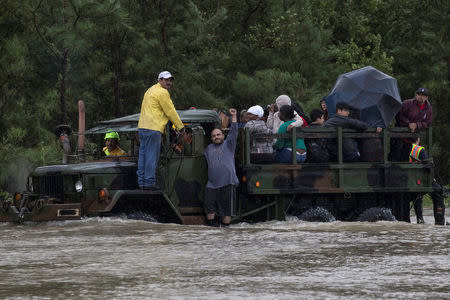 A man wearing a Houston Texans shirt, the local professional American football team, raises his arm as residents are rescued by a truck from floods caused by Tropical Storm Harvey in east Houston, Texas, U.S. August 29, 2017. REUTERS/Adrees Latif