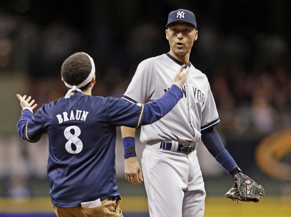 A fan runs out on the field to New York Yankees' Derek Jeter in the sixth inning of a baseball game against the Milwaukee Brewers, Friday, May 9, 2014, in Milwaukee. (AP Photo/Jeffrey Phelps)