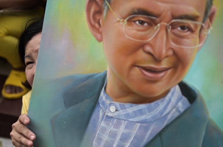 Thai well-wishers hold portraits of King Bhumibol Adulyadej