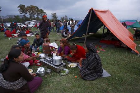 Family members eat their dinner in front of a makeshift shelter on open ground to keep safe after an earthquake in Kathmandu, Nepal April 26, 2015, a day after a 7.9 magnitude earthquake killed more than 2,400 people and devastated Kathmandu valley. REUTERS/Navesh Chitrakar