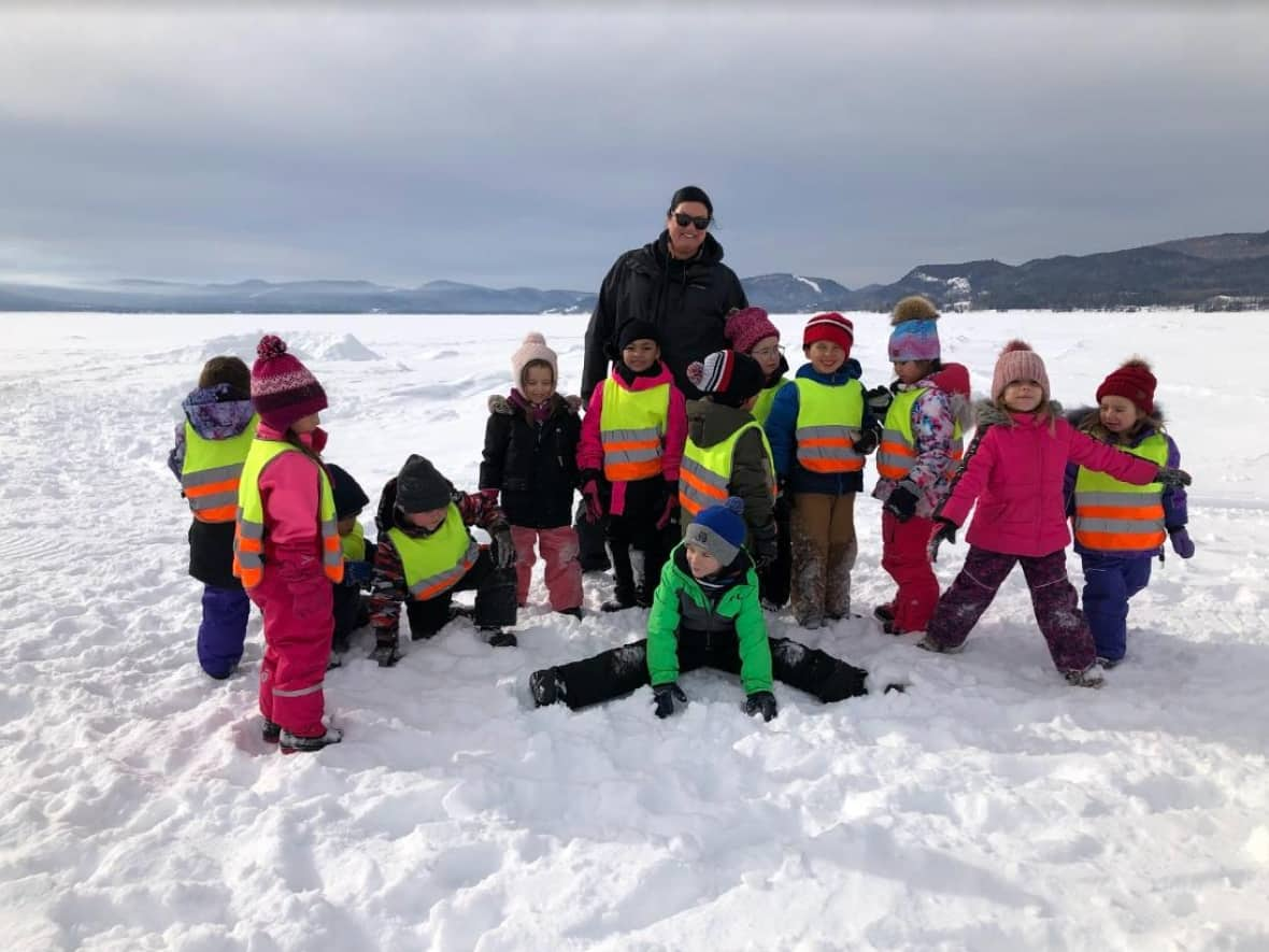 Brenda Germain, a teacher at Alaqsitew Gitpu School, tries to corral her students for a photo during an ice-fishing expedition on Chaleur Bay, in February 2023. (Julia Page/CBC - image credit)