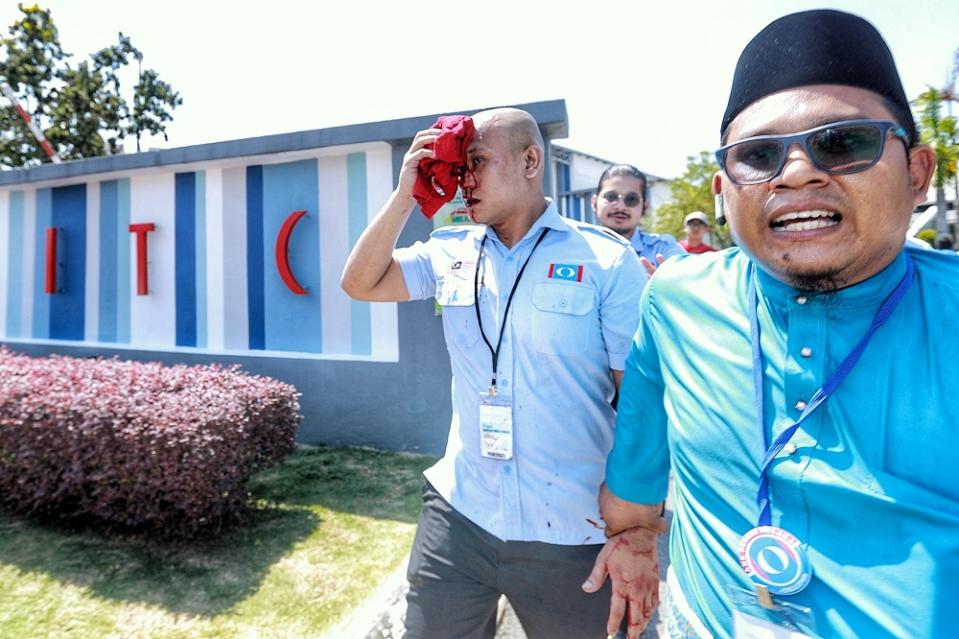 An injured PKR member is led away following a brawl that took place outside the Melaka International Trade Centre complex in Melaka December 6, 2019. — Picture by Ahmad Zamzahuri