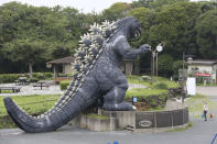 A woman wearing a face mask to protect against the spread of the new coronavirus stands near a Godzilla's slide at Kurihama flower park in Yokosuka, near Tokyo Wednesday, July 15, 2020. (AP Photo/Koji Sasahara)