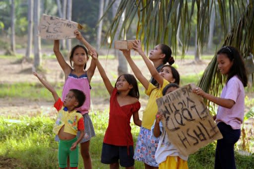 Children hold up placards on a street in Cagayan de Oro, on December 24. Thousands of people in the southern Philippines are spending Christmas in emergency shelters after floods that left more than 1,000 people dead and another 1,000 unaccounted for