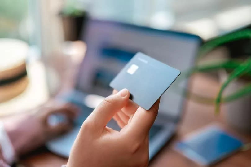 Woman paying for tickets on vacation. Online travel booking using computer. Business trip planning. Selective focus. Credit card in hand close up