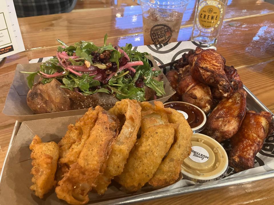 This hefty dinner at Boss ChickNBeer is comprised of chicken wings, onion rings and a sweet potato stuffed with cranberry salad. The dipping sauces pictured are mustard and barbecue sauce.