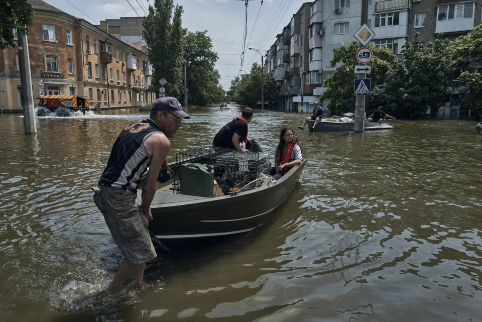 People with pets are evacuated on a boat from a flooded neighbourhood in Kherson, Ukraine, Thursday, June 8, 2023. Floodwaters from a collapsed dam kept rising in southern Ukraine on Thursday, forcing hundreds of people to flee their homes in a major emergency operation that brought a dramatic new dimension to the war with Russia, now in its 16th month. (AP Photo/Libkos)