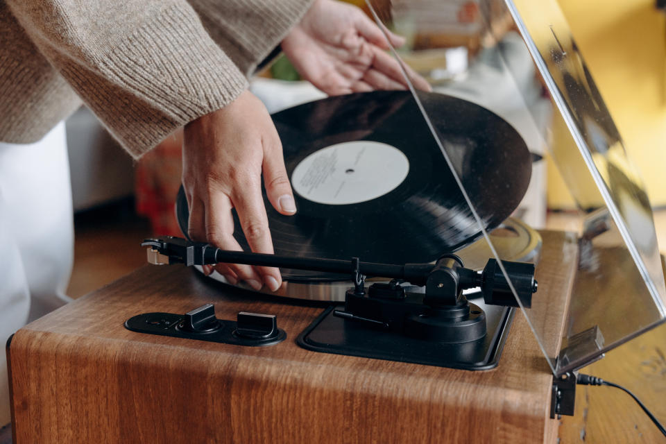 Person placing a vinyl record on a turntable, highlighting the nostalgia of music in parenting