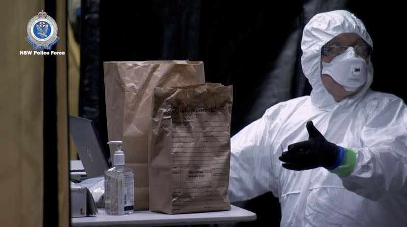 A NSW Police personnel in personal protective equipment reacts during the Strike Force Bast raid of the Ruby Princess cruise ship at Port Kembla