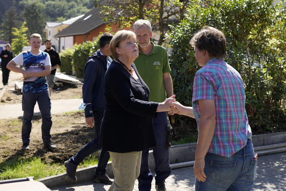 German Chancellor Angela Merkel, left, shakes hands with residents during their visit to the flood-damaged Altenahr, Germany, Friday, Sept. 3, 2021. After days of extreme downpours causing devastating floods hit the valley of the river Ahr in July. (AP Photo/Markus Schreiber, Pool)