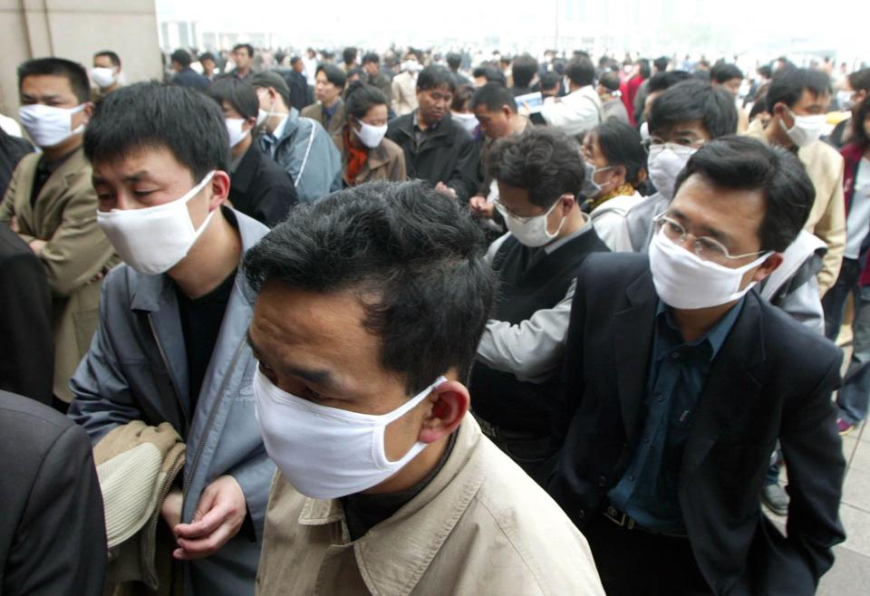 People wear masks as protection against the SARS virus as they wait to buy tickets at the Beijing Railway Station Wednesday, April 23, 2003.