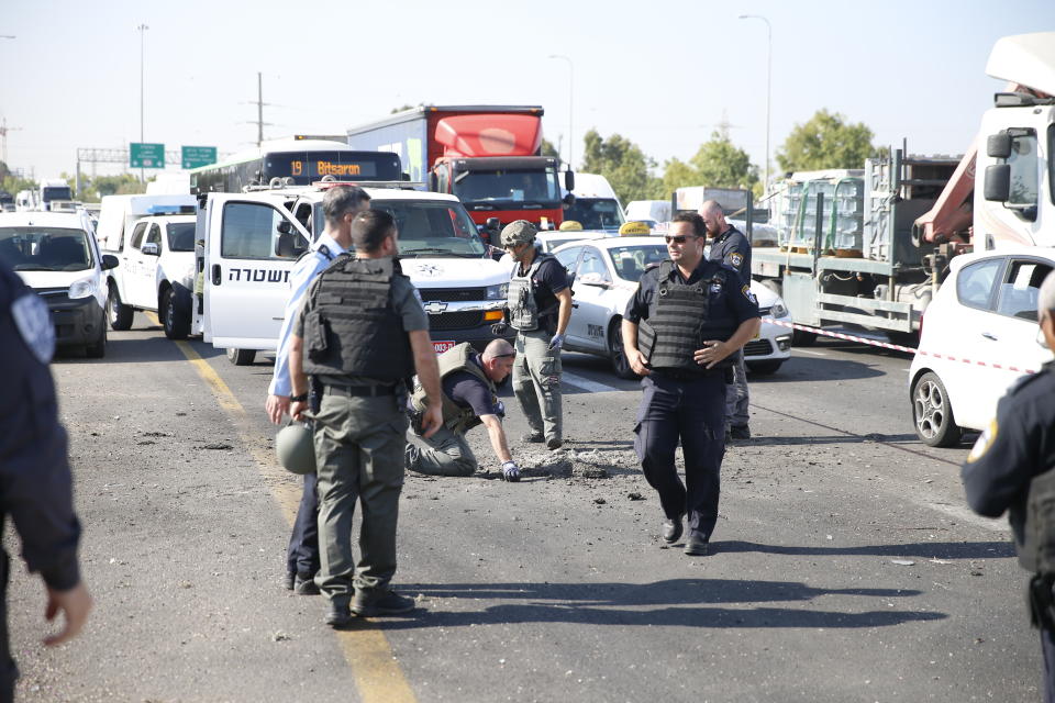 Israeli police officers examine the site moments after a rocket fired by Palestinians militants from Gaza hit a main free way between Ashdod and Tel Aviv near Ashdod Israel, Tuesday, Nov. 12, 2019. Israel has killed a senior Islamic Jihad commander in Gaza in a rare targeted killing that threatened to unleash a fierce round of cross-border violence with Palestinian militants. (AP Photo/Ariel Schalit)