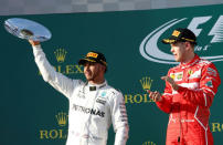 Formula One - F1 - Australian Grand Prix - Melbourne, Australia - 26/03/17 - Ferrari driver Sebastian Vettel of Germany (R) watches on as second-placed Mercedes driver Lewis Hamilton of Britain holds up his trophy. REUTERS/Brandon Malone