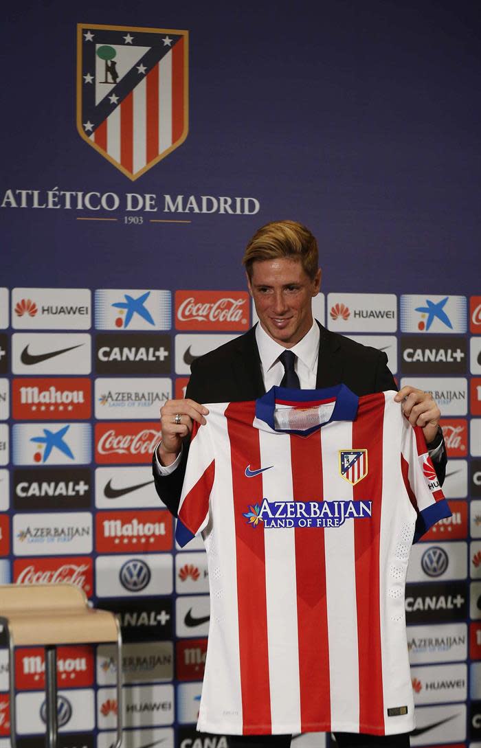 El delantero Fernando Torres muestra la camiseta que lucirá con el Atlético de Madrid durante su presentación como nuevo jugador rojiblanco, en su regreso cedido hasta el 30 de junio de 2016, esta mañana en el estadio Vicente Calderón. EFE/Paco Campos