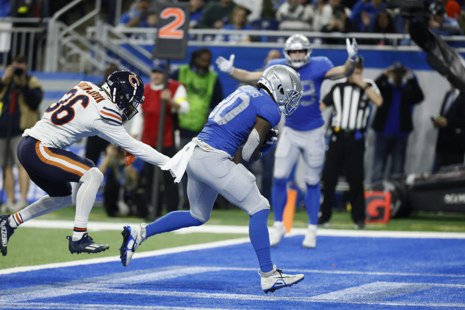 Detroit Lions running back Jamaal Williams (30), defended by Chicago Bears safety DeAndre Houston-Carson (36), runs for a 2-yard rushing touchdown during the second half of an NFL football game, Sunday, Jan. 1, 2023, in Detroit. (AP Photo/Duane Burleson)