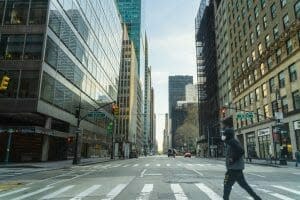 A man crosses a street in an empty city.