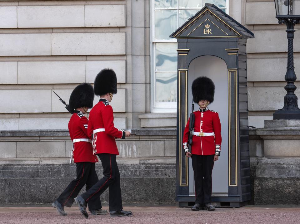 A Guardsman is brought water as he stands sentry outside Buckingham Palace.