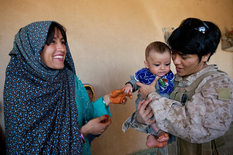 BOLDOC, AFGHANISTAN - NOVEMBER 23: (SPAIN OUT, FRANCE OUT, AFP OUT) Lance Corporal Luz Lopez, 21, a US Marine with the FET (Female Engagement Team) 1st Battalion 8th Marines, Regimental Combat team II holds an Afghan baby during a village medical outreach on November 23, 2010 in Boldoc, in Helmand province, Afghanistan. There are 48 women presently working along the volatile front lines of the war in Afghanistan deployed as the second Female Engagement team participating in a more active role, gaining access where men can't. The women, many who volunteer for the 6.5 month deployment take a 10 week course at Camp Pendleton in California where they are trained for any possible situation, including learning Afghan customs and basic Pashtun language. (Photo by Paula Bronstein/Getty Images)