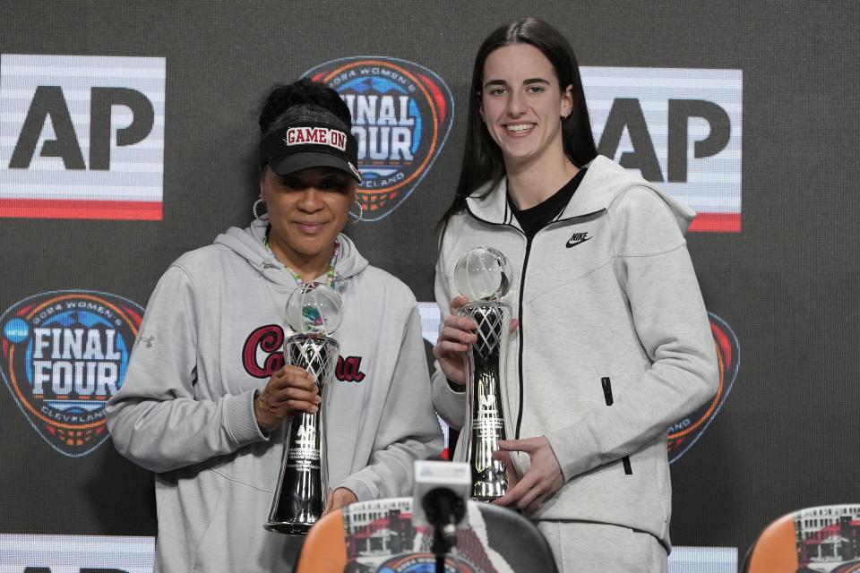 Iowa's Caitlin Clark and South Carolina head coach Dawn Staley post with their awards after a news conference announcing the AP NCAA Women's Coach and Player of the Year Thursday, April 4, 2024, in Cleveland. (AP Photo/Morry Gash)