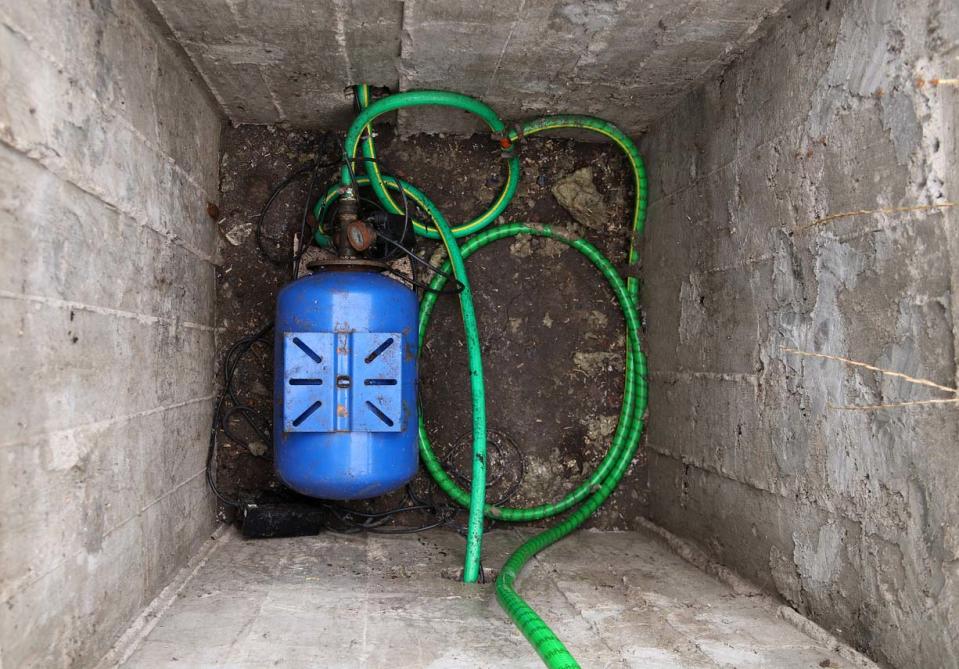A view of a sewage ejector pump in a cinder block lined hole.