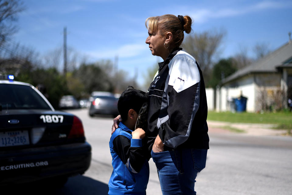 <p>Isaac Machado hides behind his hat against his mother Delores just outside the scene of an explosion on Galindo Street in Austin, Texas, March 12, 2018. (Photo: Sergio Flores/Reuters) </p>