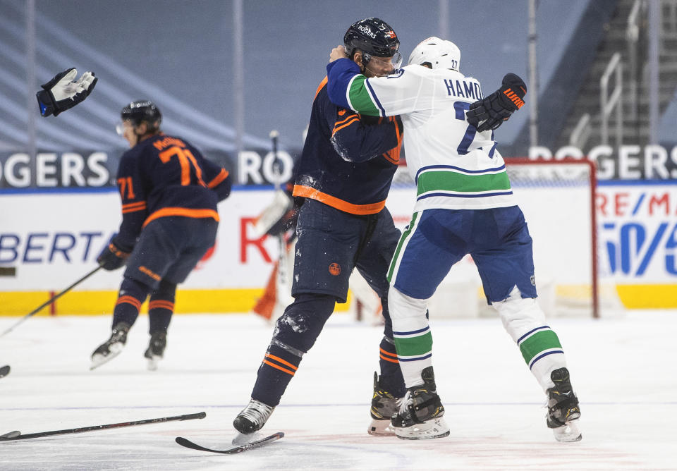 Edmonton Oilers' Alex Chiasson (39) and Vancouver Canucks' Travis Hamonic (27) fight during second-period NHL hockey game action in Edmonton, Alberta, Thursday, May 6, 2021.. (Jason Franson/The Canadian Press via AP)