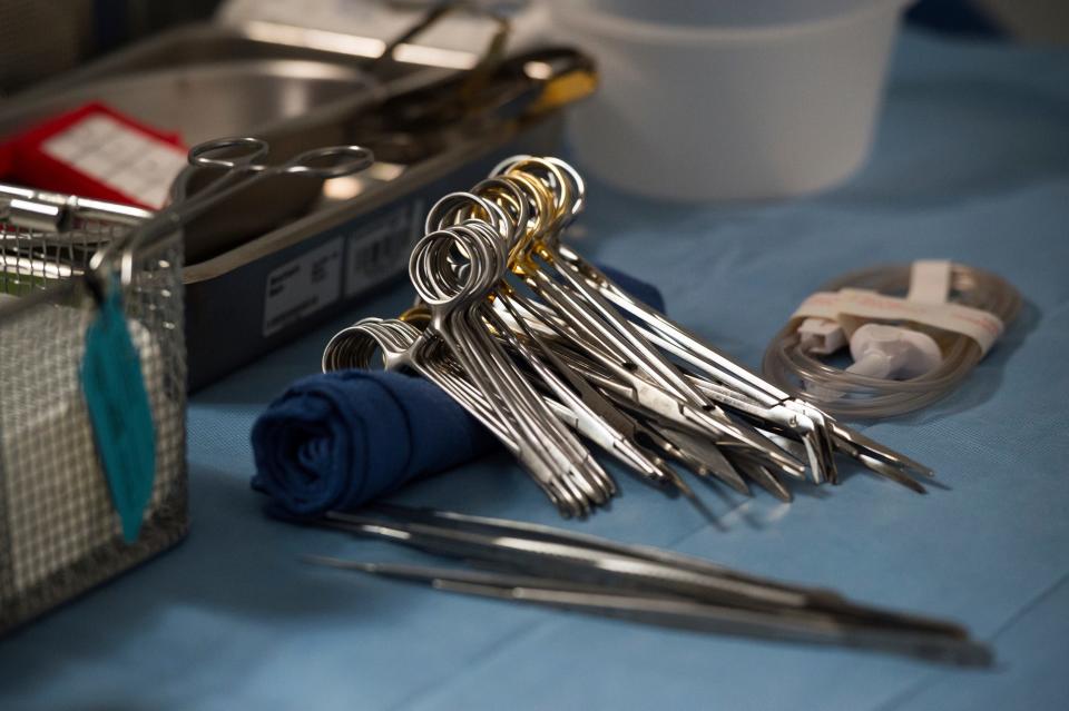 Surgical instruments and supplies lay on a table in an operating room.
