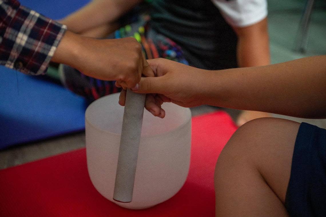 Guests practice using a yoga singing bowl during a meditation class at Newhouse on Tuesday, June 20, 2023, in Kansas City.