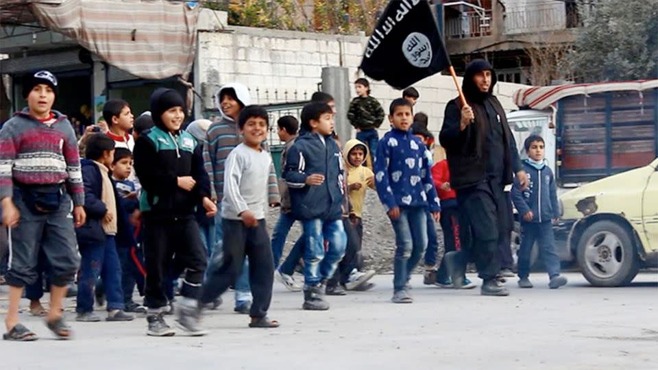 Islamic State militant, right, holding his group's flag, during a street preaching session in al-Tabqa in Raqqa province, northeast Syria. Photo: Militant website via AP