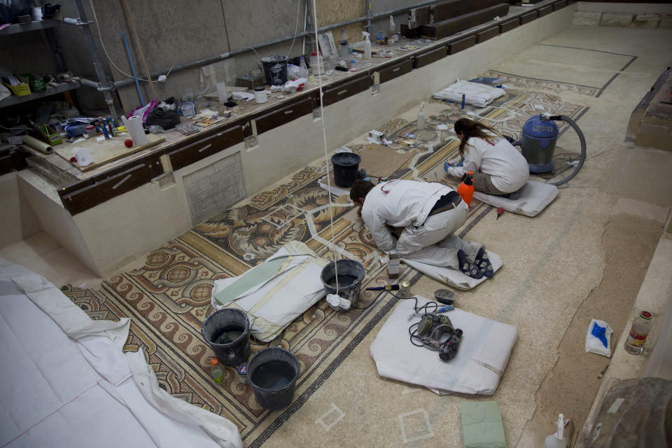 In this Thursday, Dec. 6, 2018 photo, restoration experts work on a mosaic inside the Church of the Nativity, built atop the site where Christians believe Jesus Christ was born, in the West Bank City of Bethlehem. City officials are optimistic that the renovated church will help add to a recent tourism boom and give a boost to the shrinking local Christian population. (AP Photo/Majdi Mohammed)