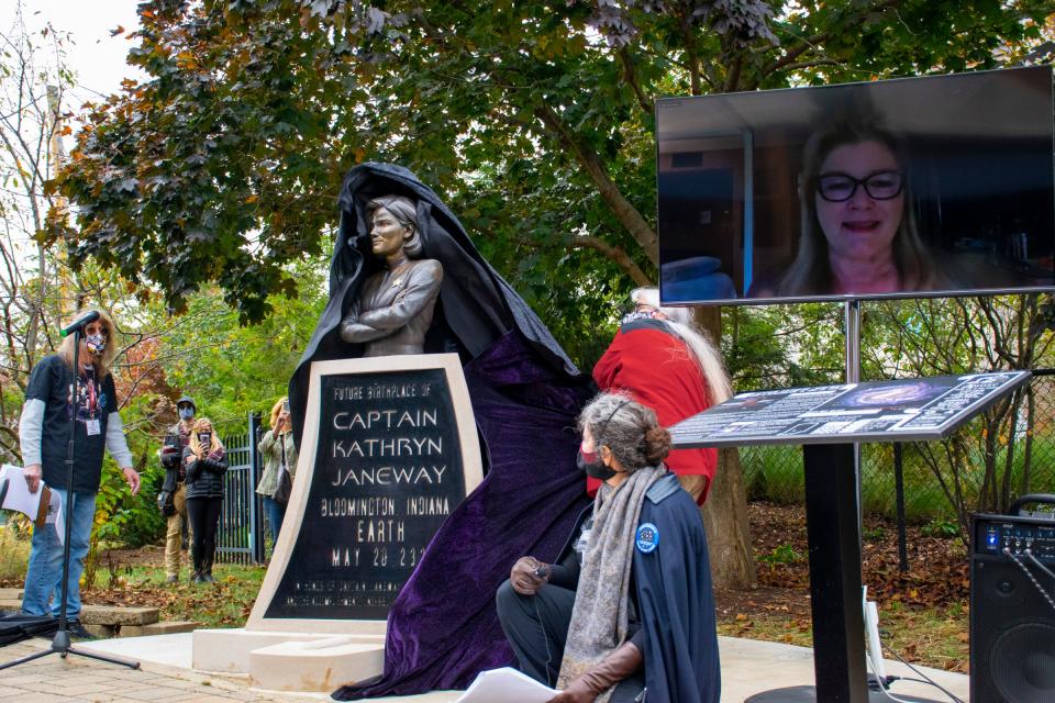 Members of the Janeway Project, Peter Kaczmarczyk, left, and Melissa Kocias, front middle, watch Mary Beth Kaczmarczyk, back middle, pull the cover off the Capt. Kathryn Janeway monument Oct. 24. Kate Mulgrew, the actress who played the role, watches live virtually, on screen. (Josh Dinner / Herald-Times)